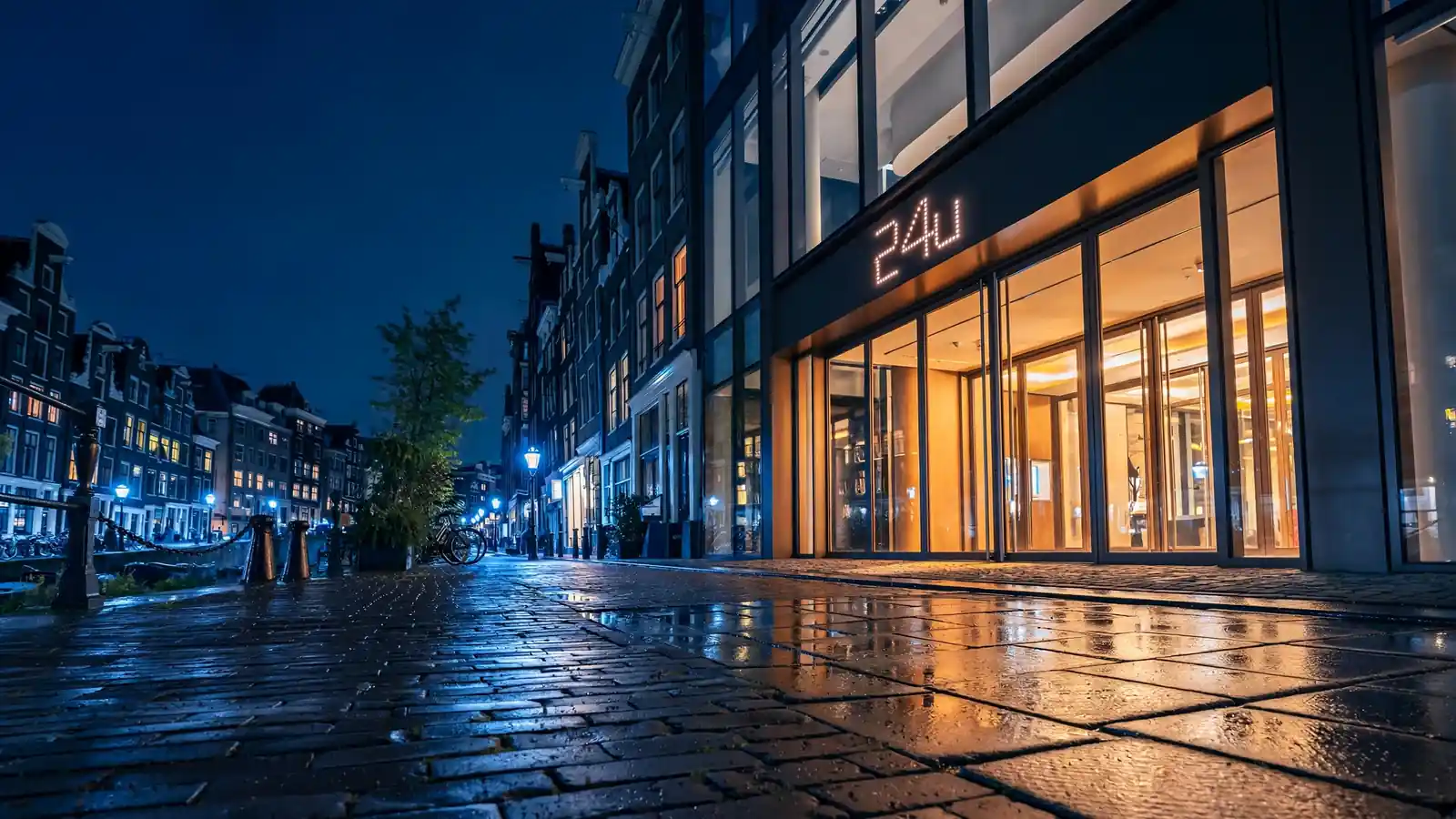 Verlichte casino-entree in Amsterdam bij nacht met 24-uur open bord